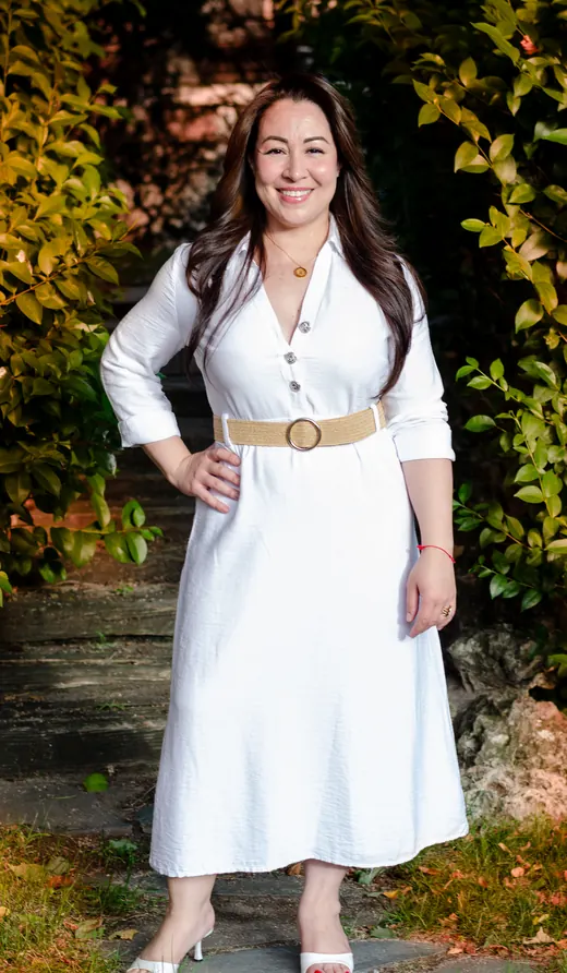 Clara Arias de pie en un jardín, vestida de blanco